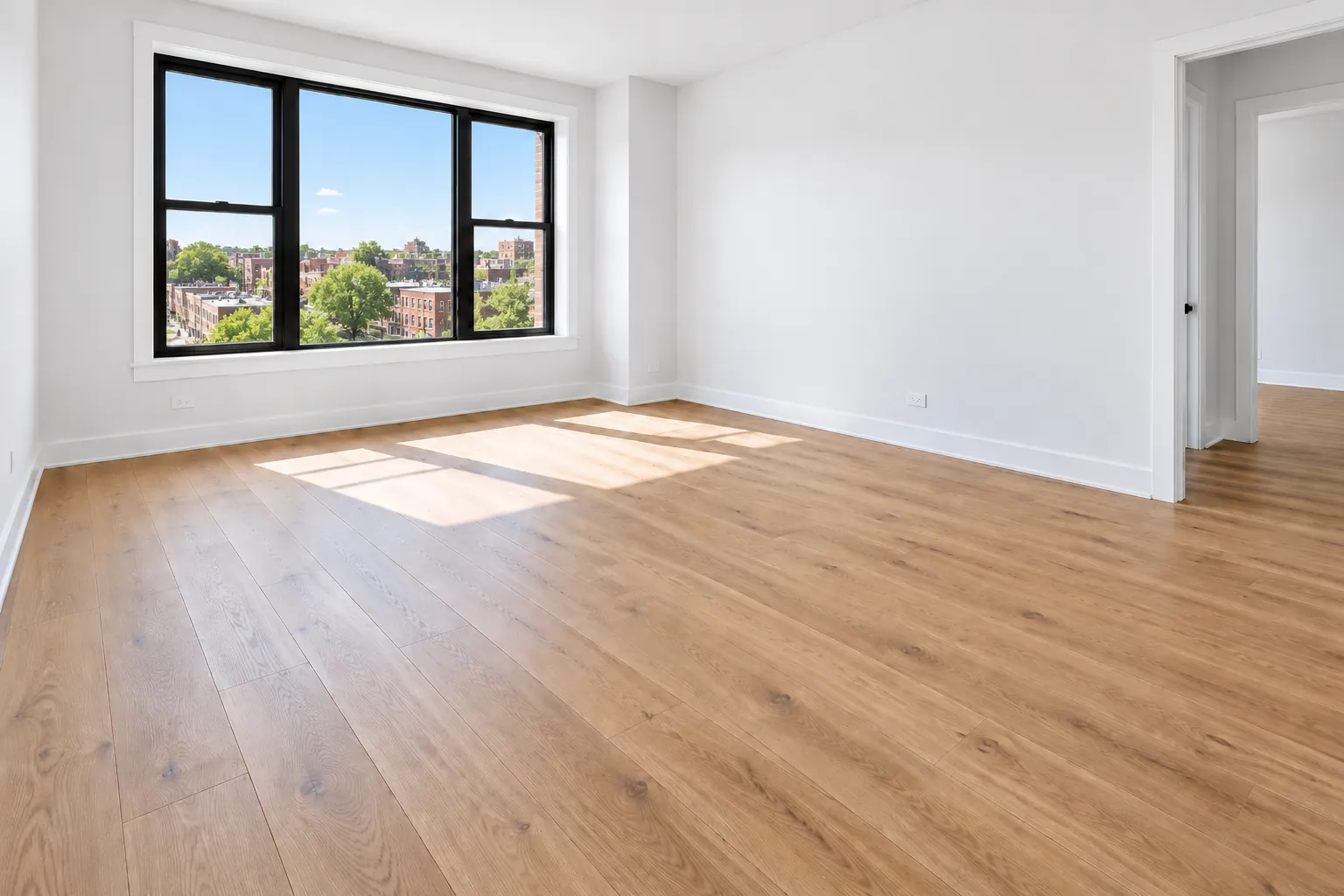 A freshly painted room with white walls, new baseboards and plank flooring